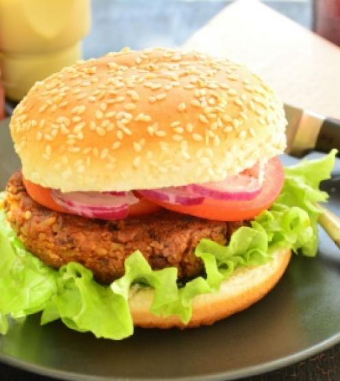 Vegetárinus hamburger, szezámmagos buciban, salátával, lilahagymával és paradicsommal